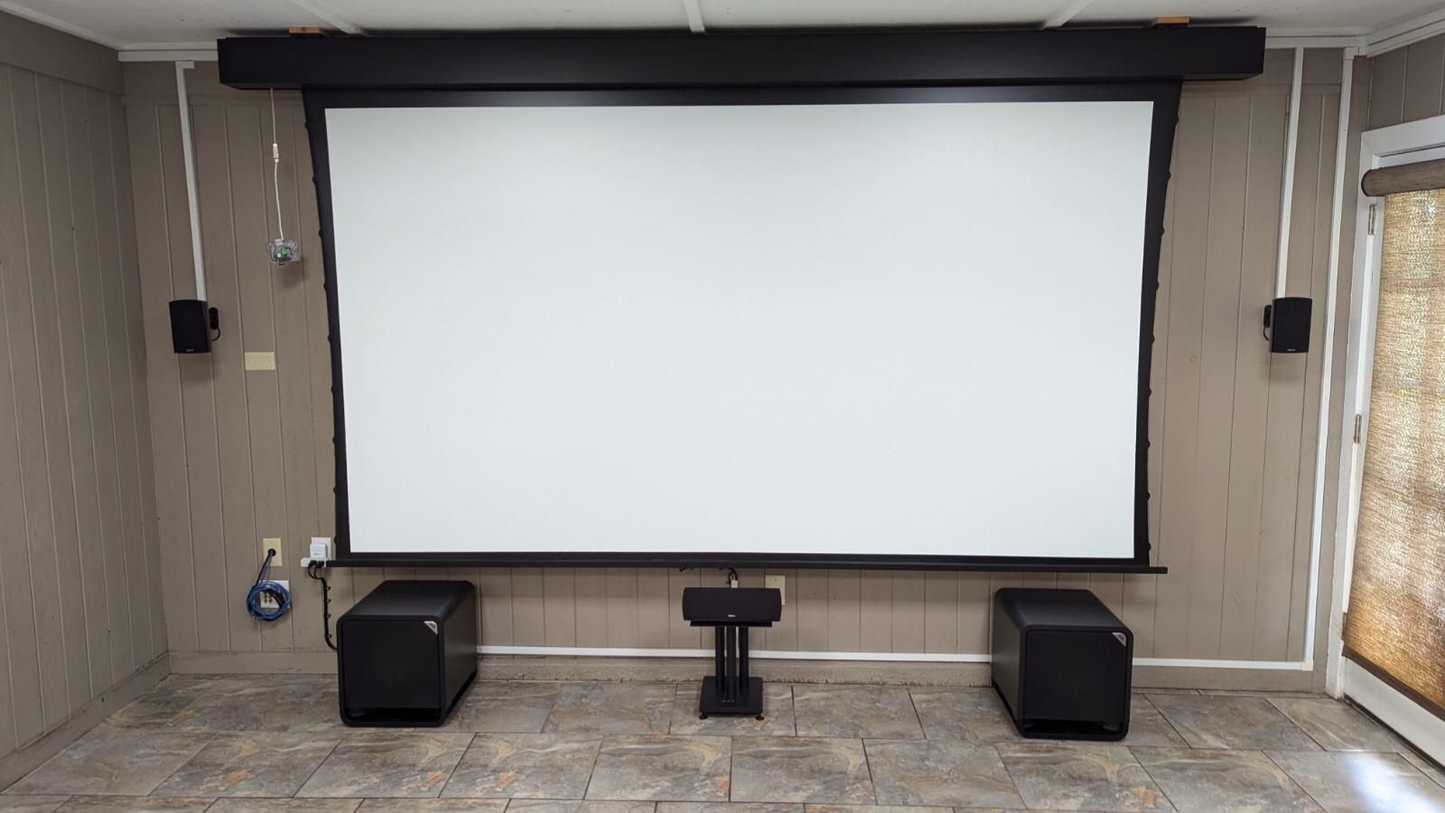 A home theater with a projector screen and speakers.