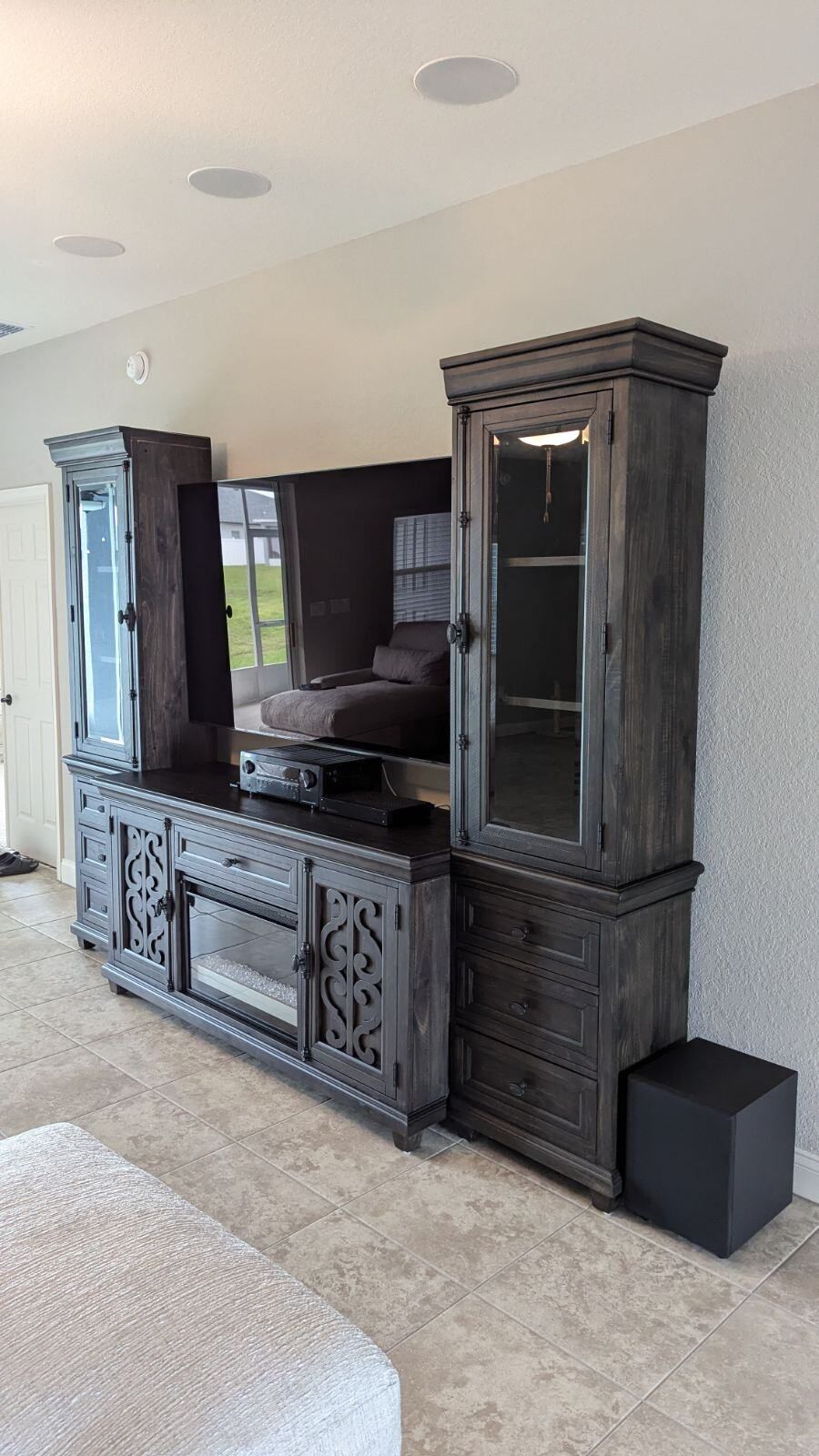 A living room with a large entertainment center and a fireplace.