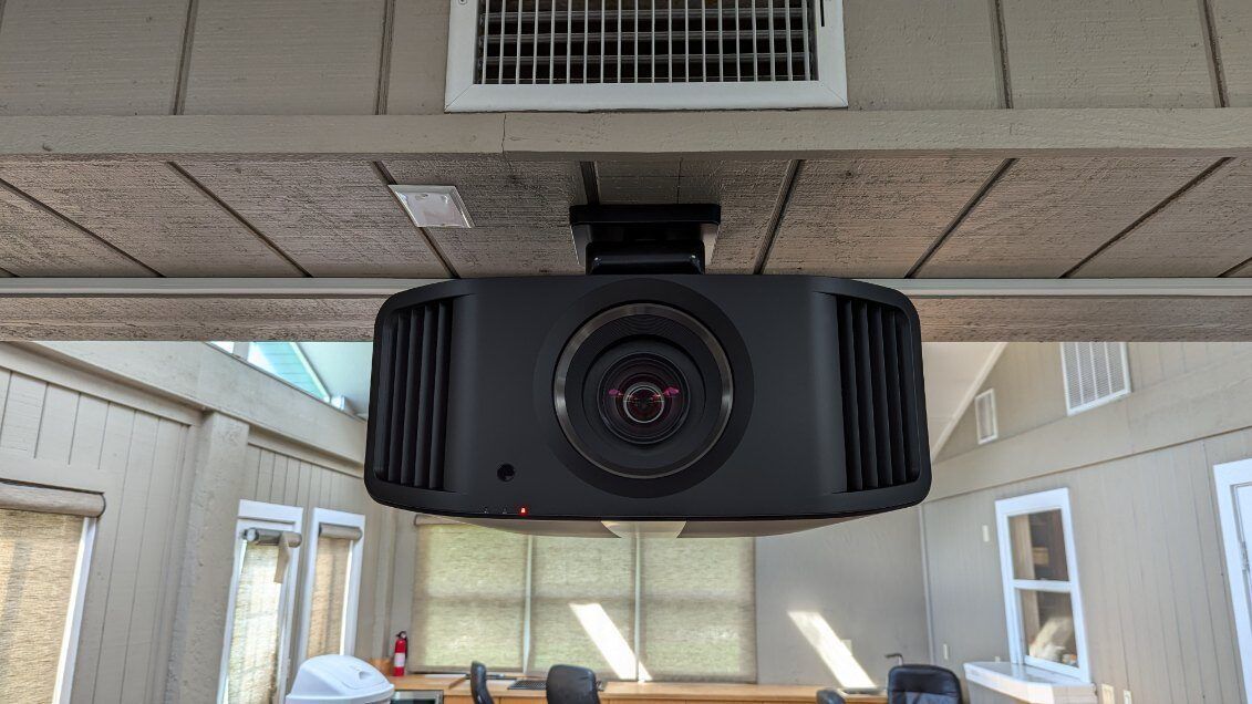 A projector is hanging from the ceiling of a room.
