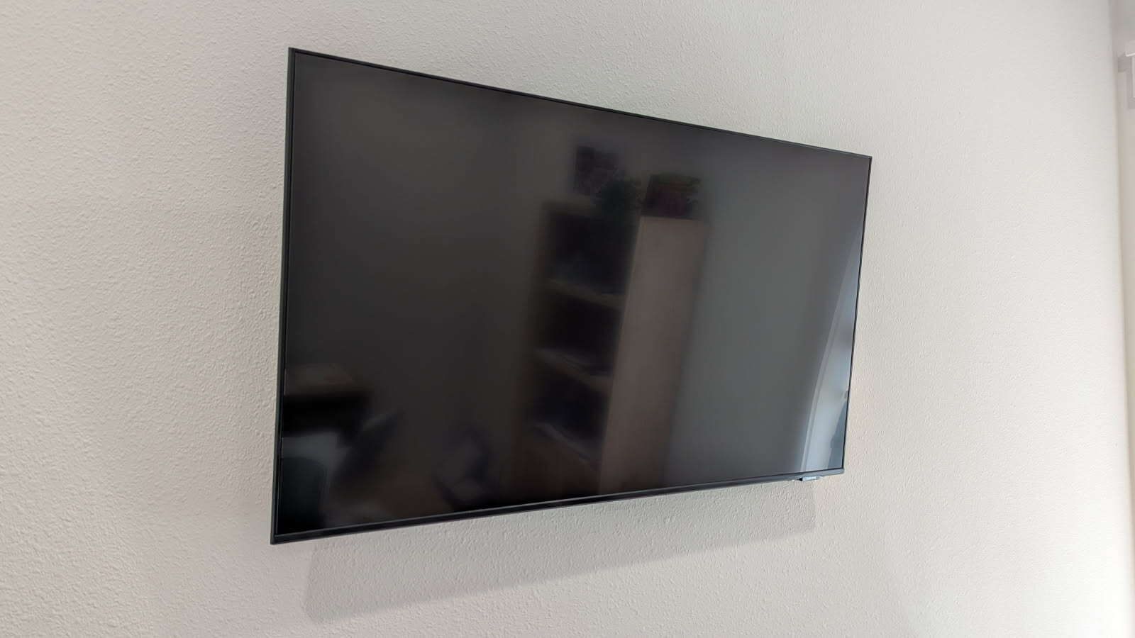 A flat screen tv is mounted on a white wall.
