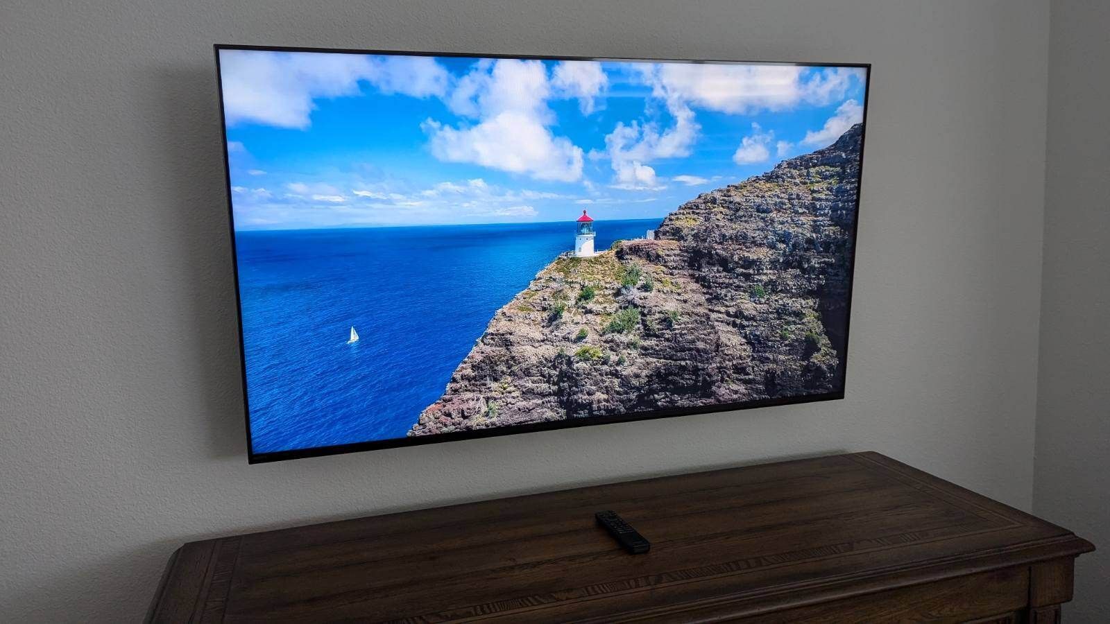 A flat screen tv is hanging on a wall above a wooden table.