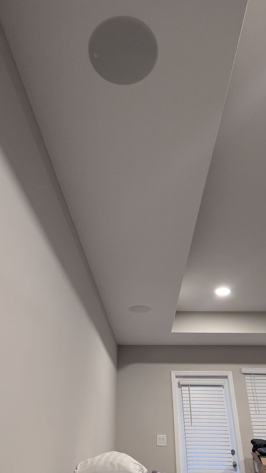 There is a speaker in the ceiling of a room.