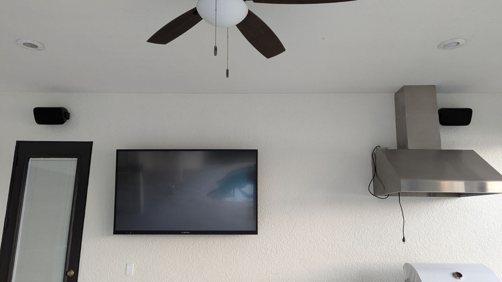 A ceiling fan is hanging from the ceiling above a flat screen tv.
