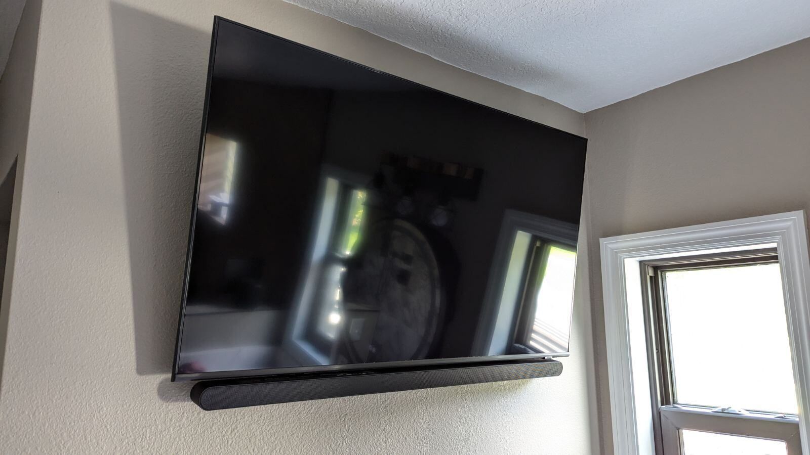A flat screen tv is mounted on a wall next to a window.
