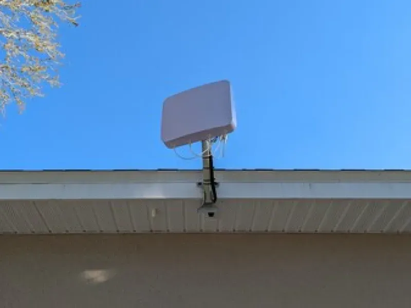 A white antenna is mounted on the roof of a house.