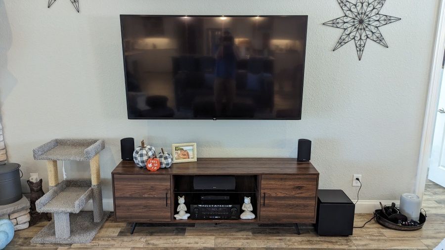 A living room with a flat screen tv mounted on the wall above a wooden entertainment center.