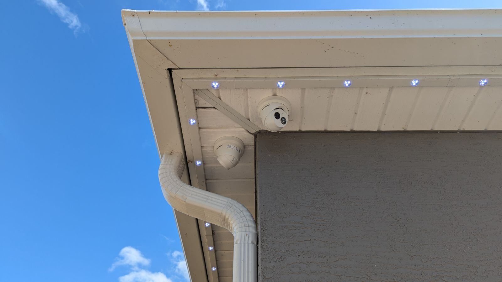 A white gutter on the side of a house with lights on it.