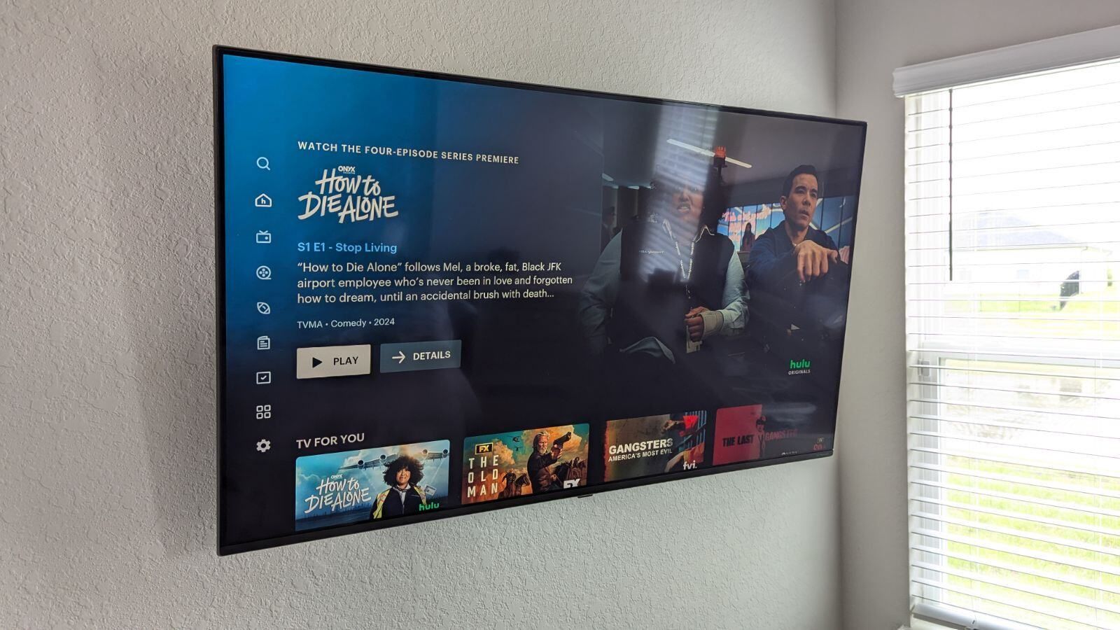 A flat screen tv is hanging on a wall next to a window.