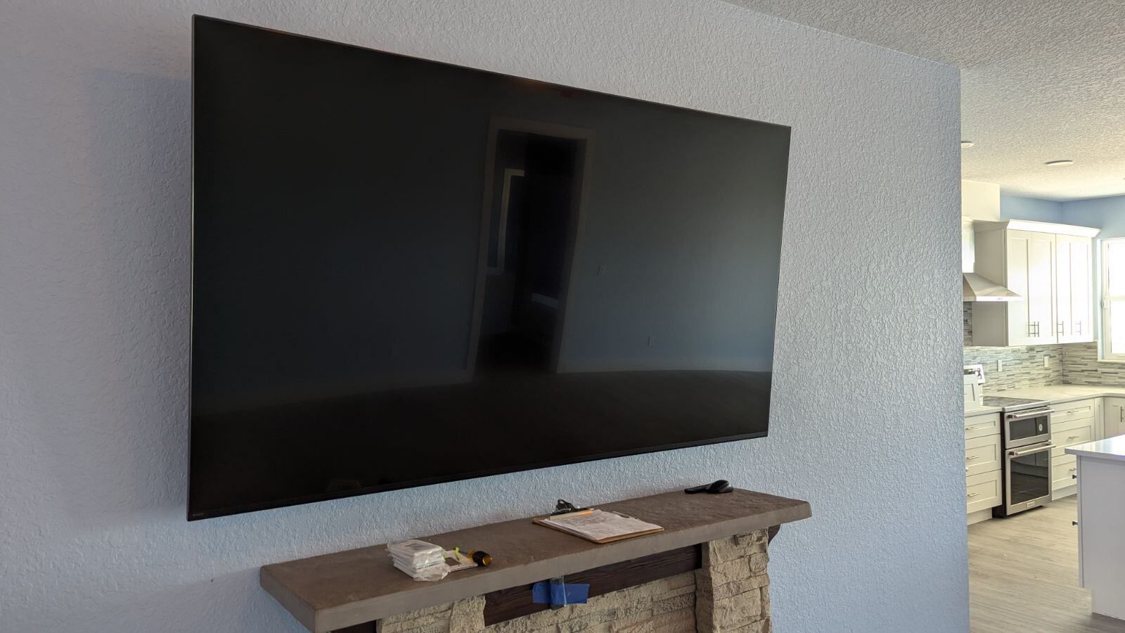 A large flat screen tv is mounted on a wall above a fireplace.
