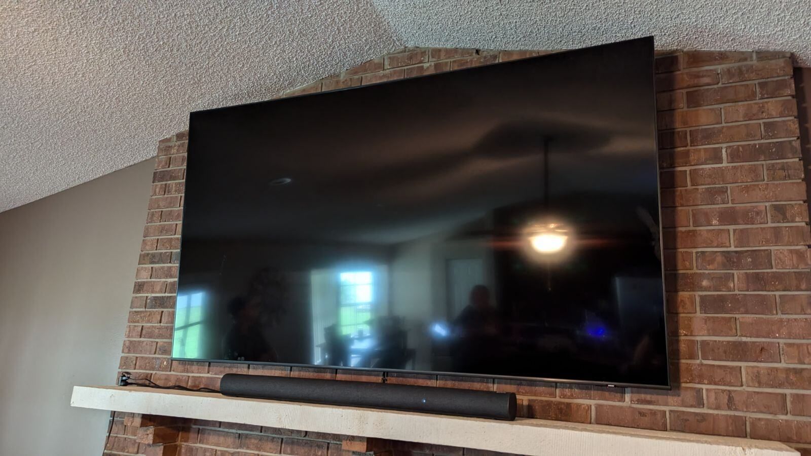 A flat screen tv is mounted on a brick wall above a fireplace.