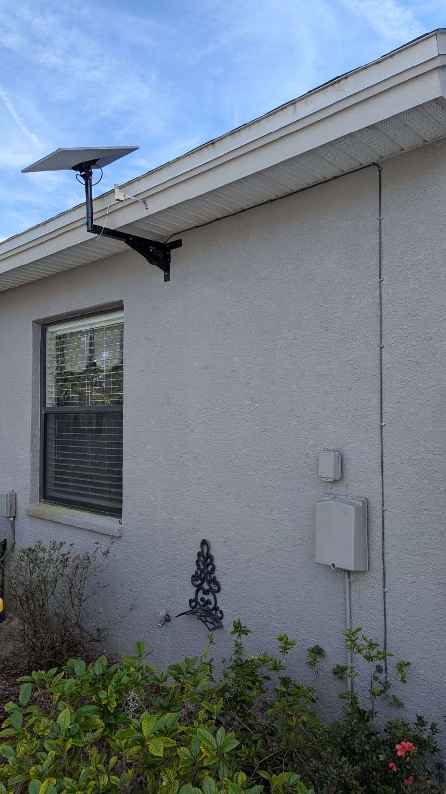 A white house with a solar panel on the side of it.