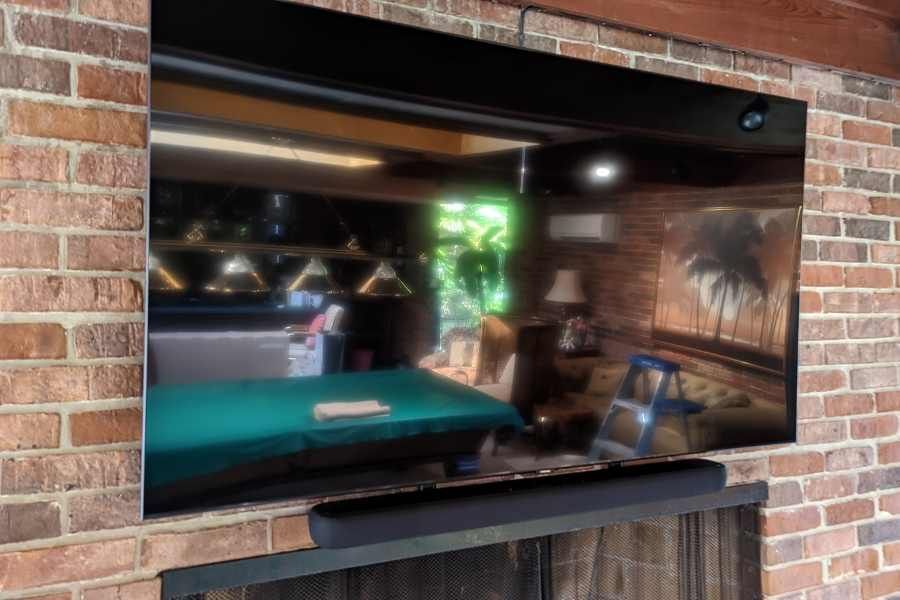A flat screen tv is mounted on a brick wall in a living room.