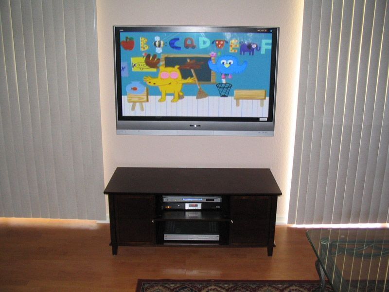 A flat screen tv is mounted on a wall above a wooden entertainment center