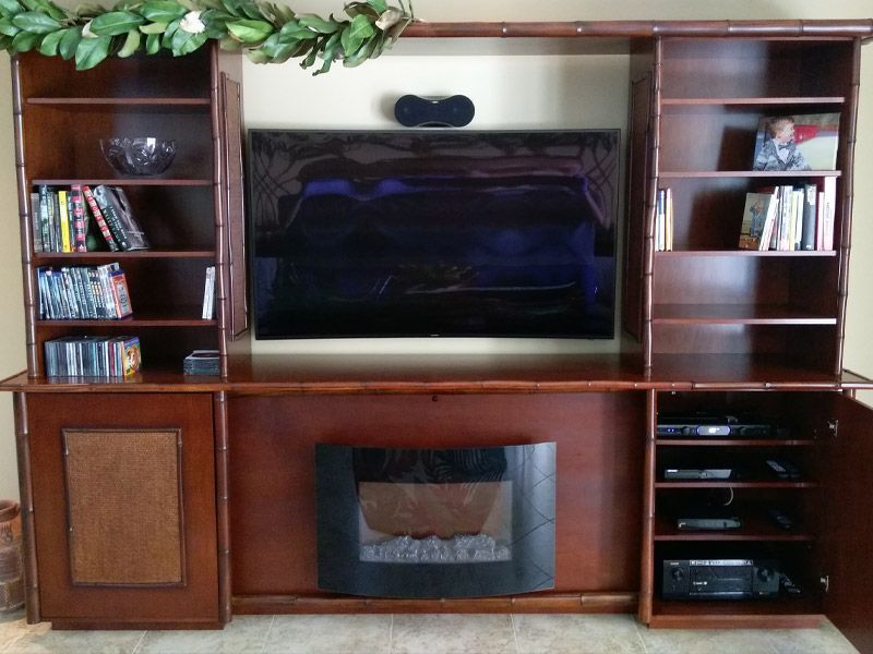 A wooden entertainment center with a fireplace and a flat screen tv