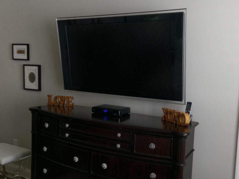 A large flat screen tv mounted on a wall above a dresser