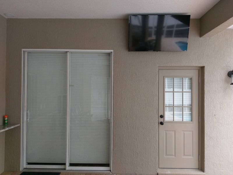 A room with a sliding glass door and a flat screen tv above it