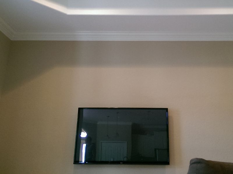 A flat screen tv is hanging on a wall in a living room.