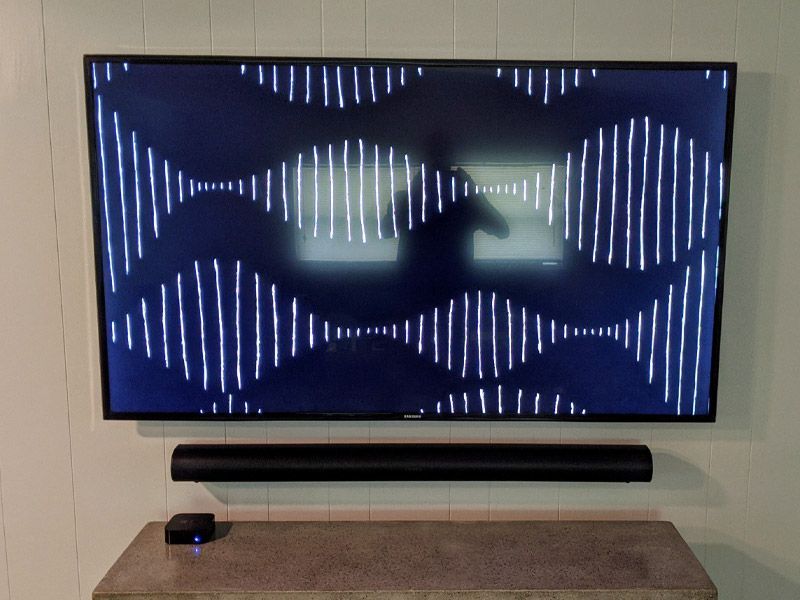 A flat screen tv is mounted to a wall next to a sound bar.