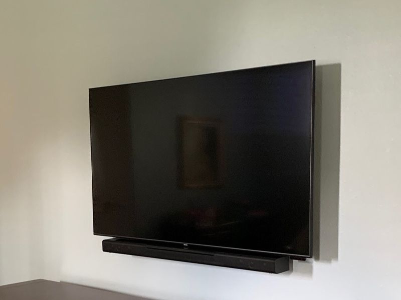A flat screen tv is mounted on a wall next to a sound bar.