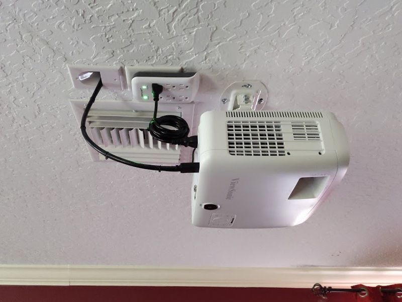 A white projector is hanging from the ceiling