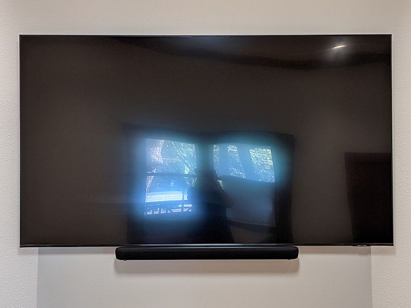A flat screen tv is mounted on a wall next to a sound bar.