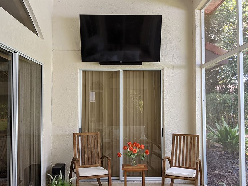 A screened in porch with chairs and a flat screen tv