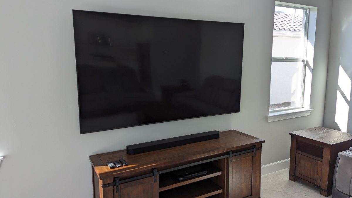 A large flat screen tv is mounted on a wall above a wooden entertainment center.