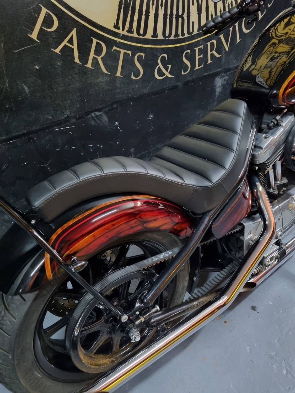 A motorcycle is parked in front of a sign that says parts & service