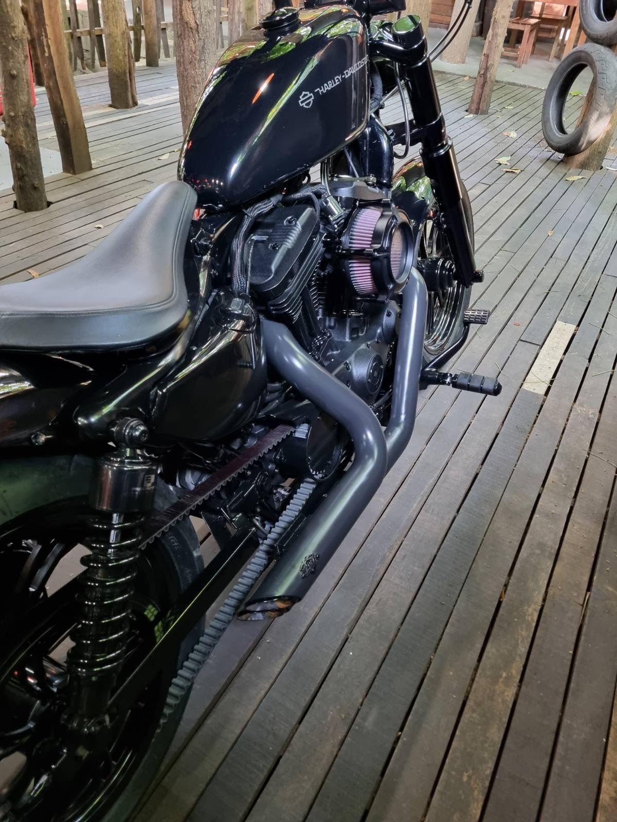 A black motorcycle is parked on a wooden deck.