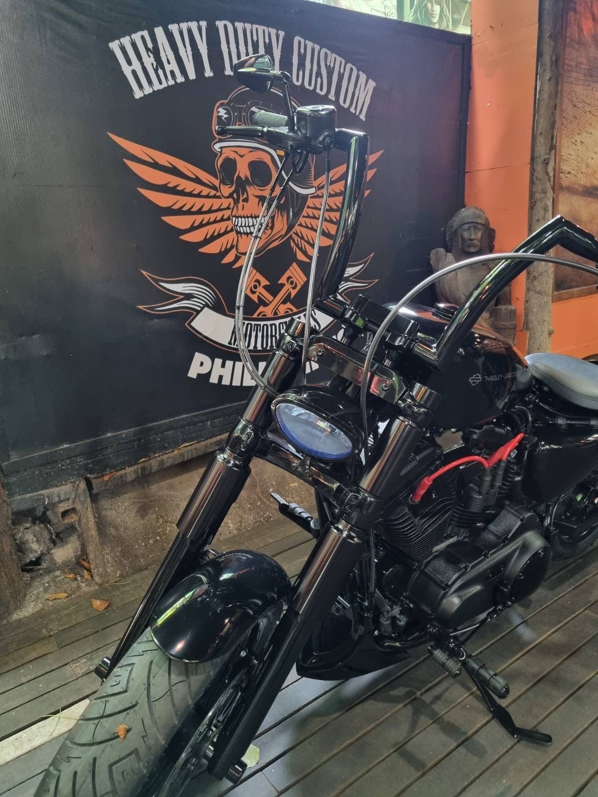 A motorcycle is parked in front of a sign that says heavy rusty custom.