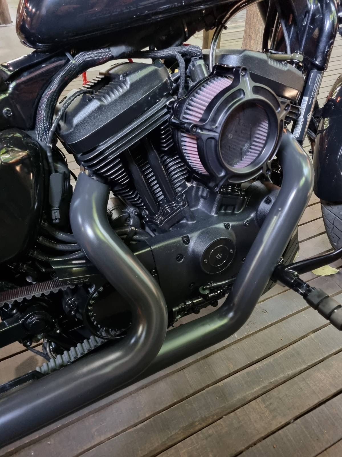 A black motorcycle is parked on a wooden deck.