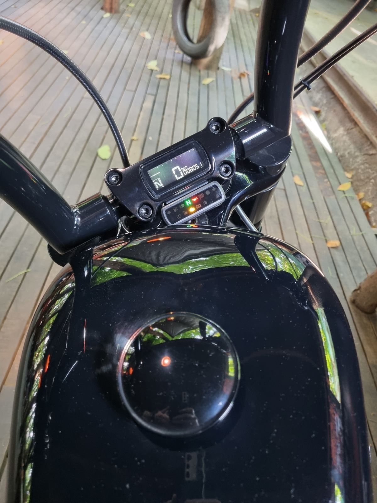 A black motorcycle is parked on a wooden deck.