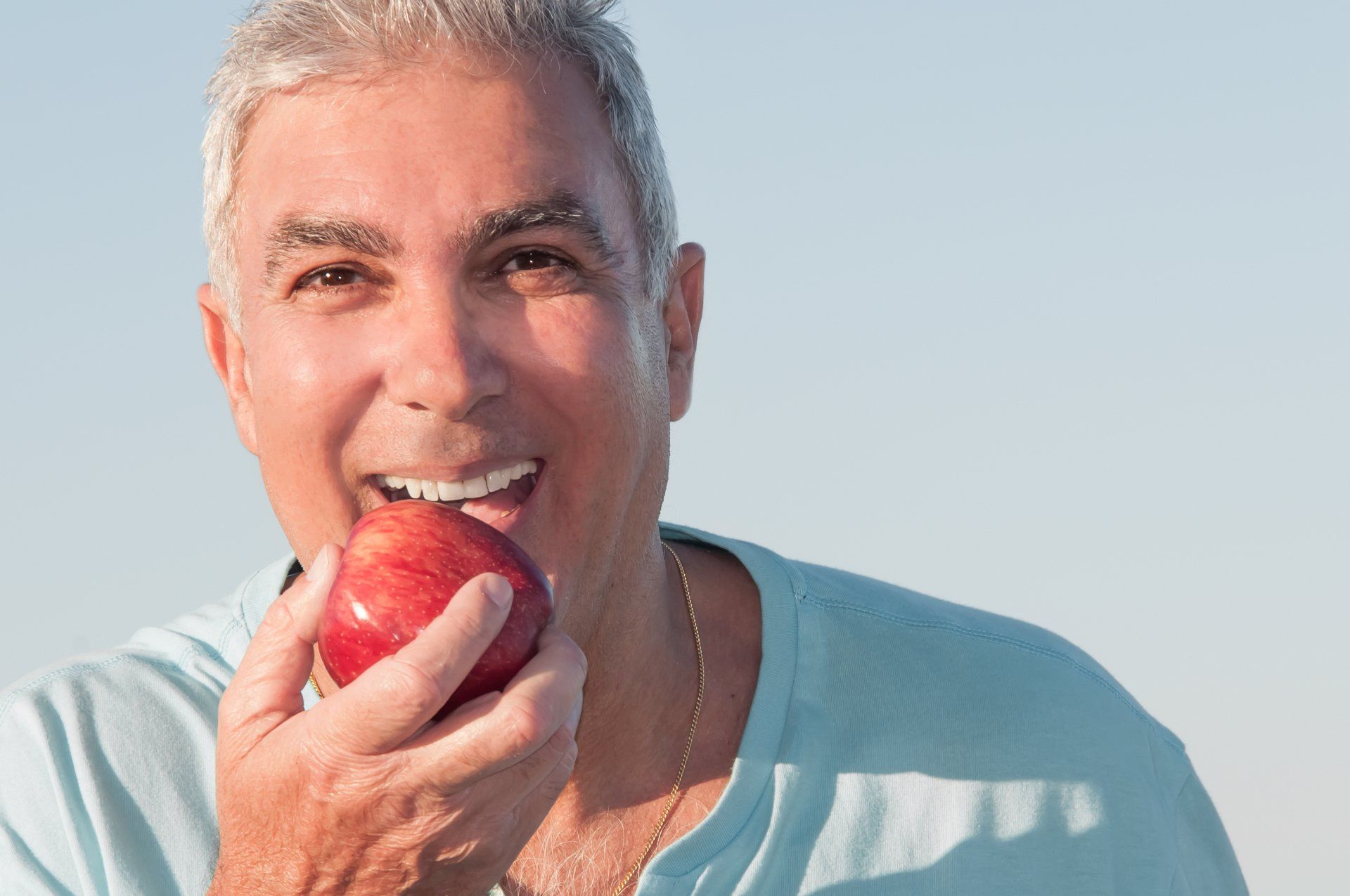 a man in a blue shirt is biting into a red apple