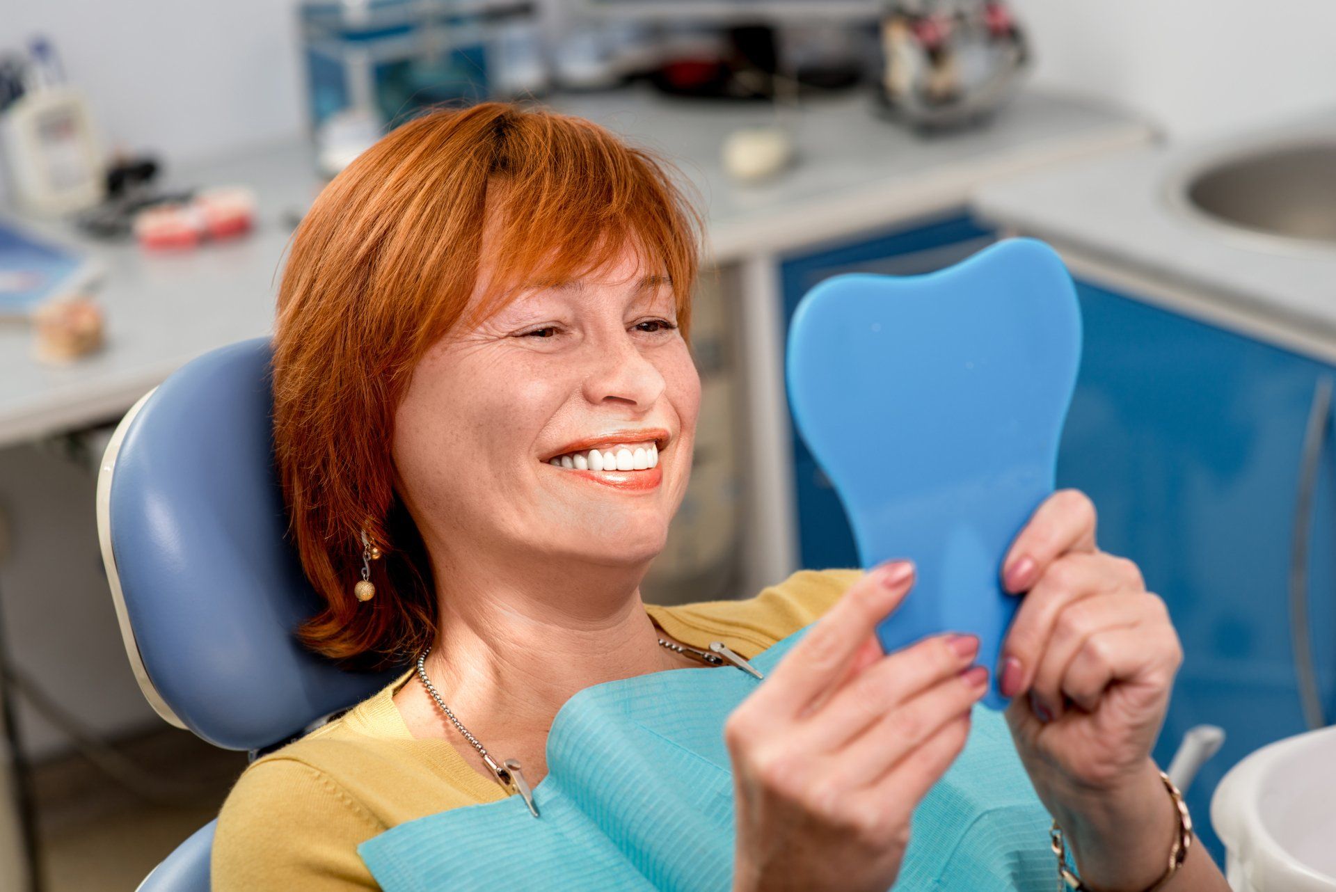 a woman in a dental chair looking at her teeth in a mirror