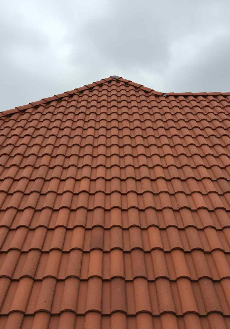Looking up at a red tiled roof with a cloudy sky in the background
