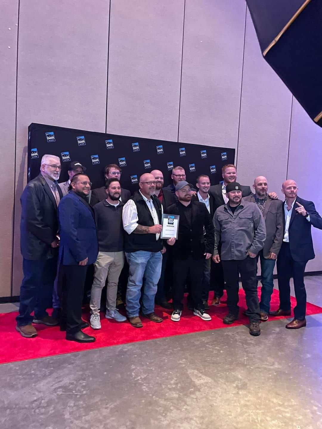 a group of men are posing for a picture in front of a wall that has a few logos on it