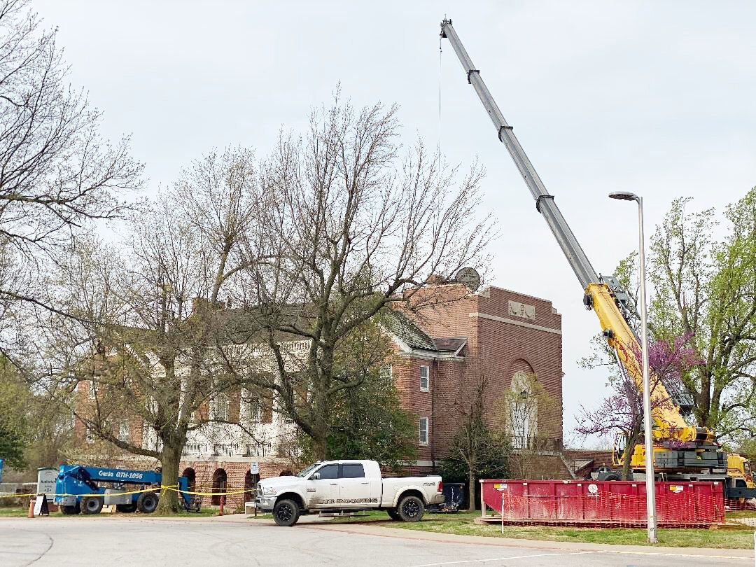 a white truck with a crane on the back is parked in front of a brick building