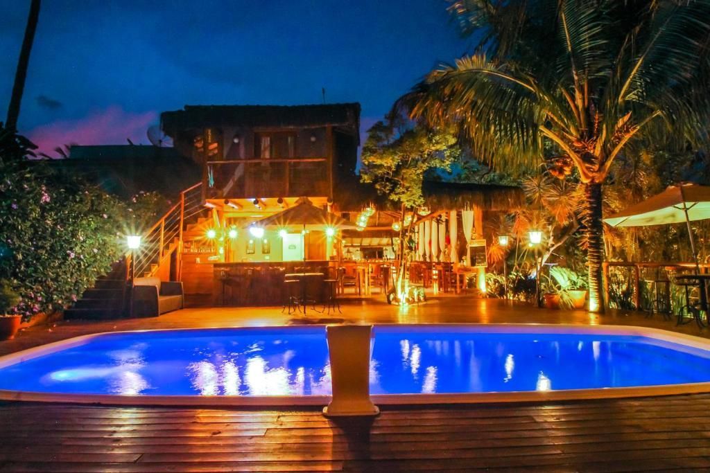 Uma grande piscina fica iluminada à noite em frente a um prédio.