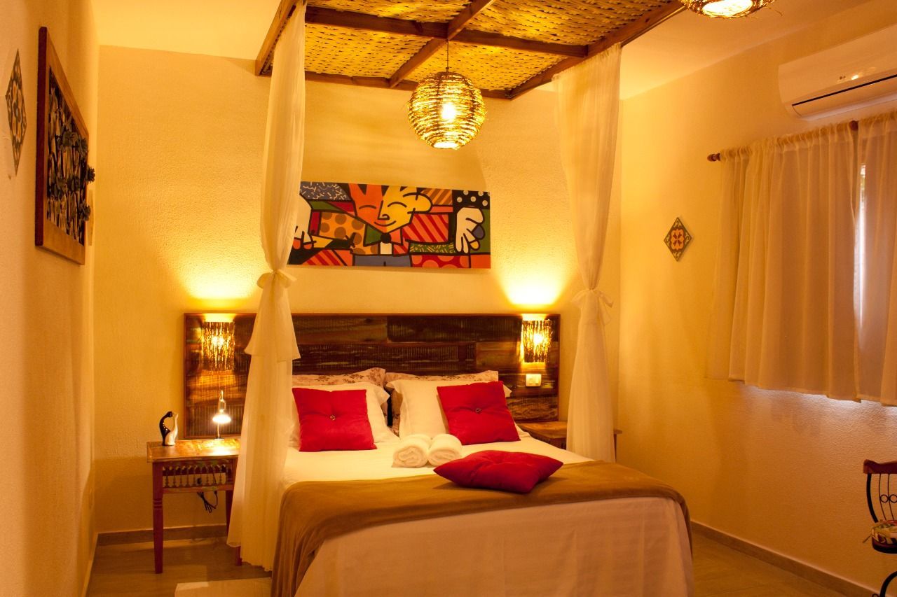 Um quarto com cama de dossel e travesseiros vermelhos