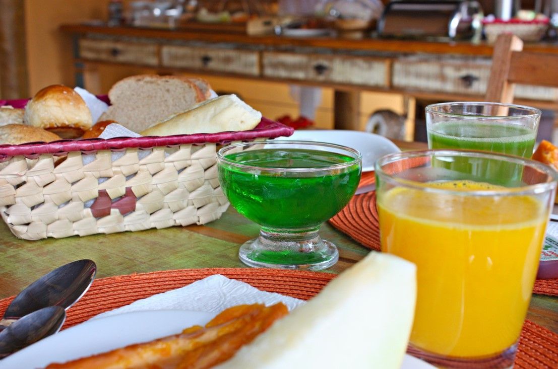 Há uma cesta de pães e um copo de suco de laranja sobre a mesa.