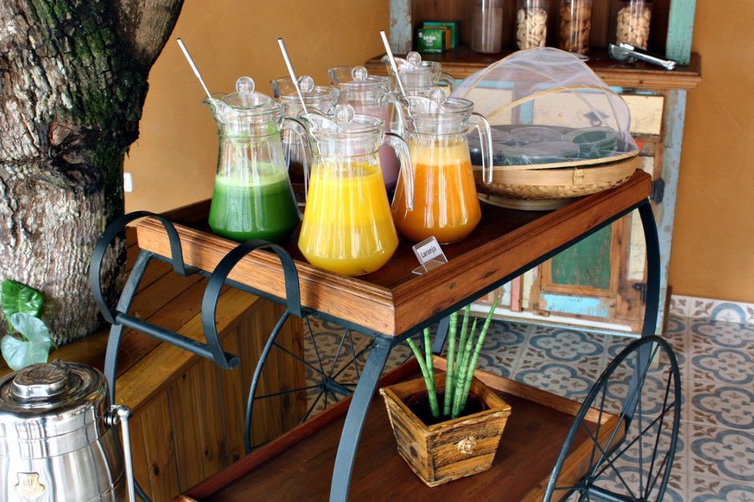 Um carrinho de madeira cheio de jarras de suco e uma planta.