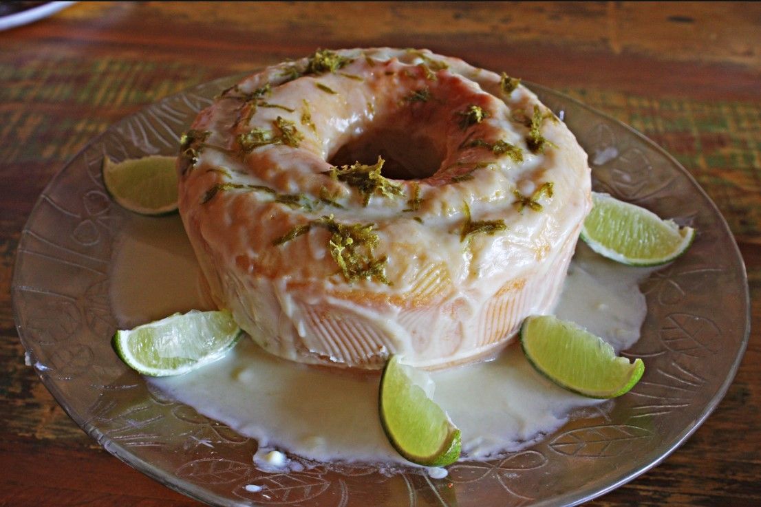 Um prato de vidro coberto com um bolo e limão sobre uma mesa de madeira.