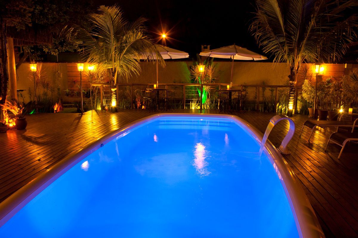 Uma grande piscina é iluminada à noite com luzes azuis.