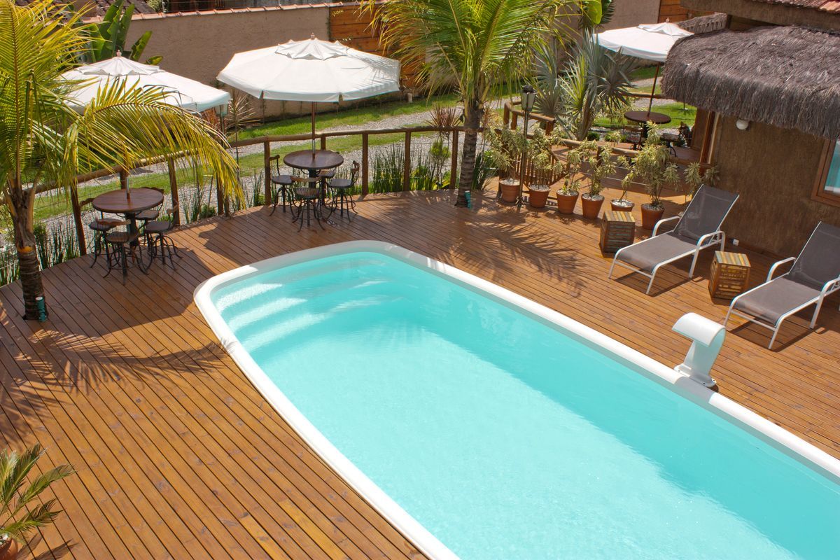 Uma vista aérea de uma piscina com mesas e cadeiras ao seu redor.