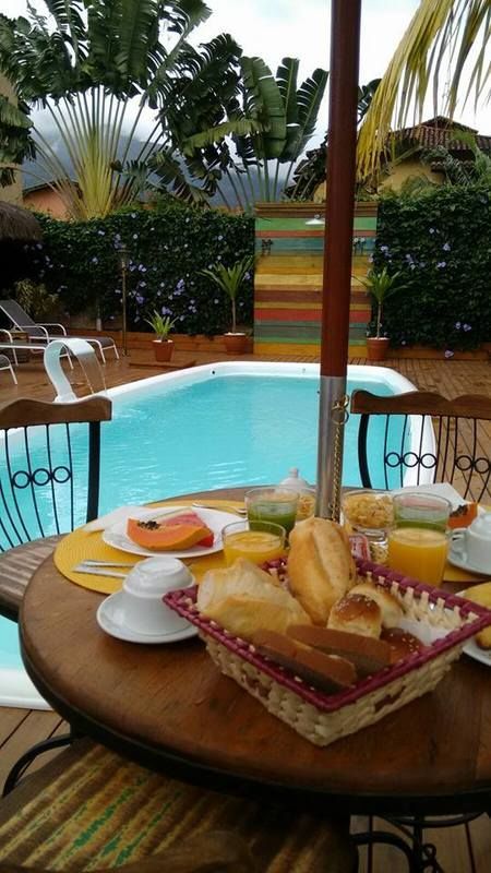 Uma mesa com uma cesta de pães em frente a uma piscina.