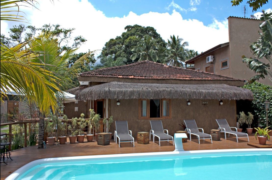 Uma piscina em frente a uma casa com telhado de palha