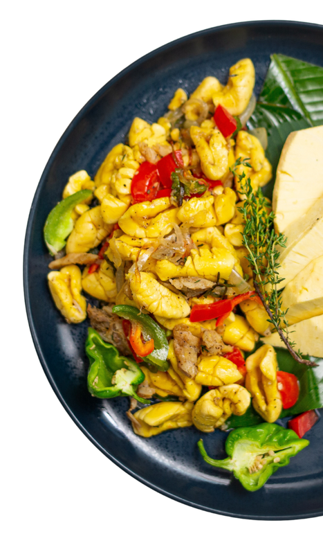 Ackee and saltfish, a Jamaican dish on a blue plate, with colorful peppers and a plantain.