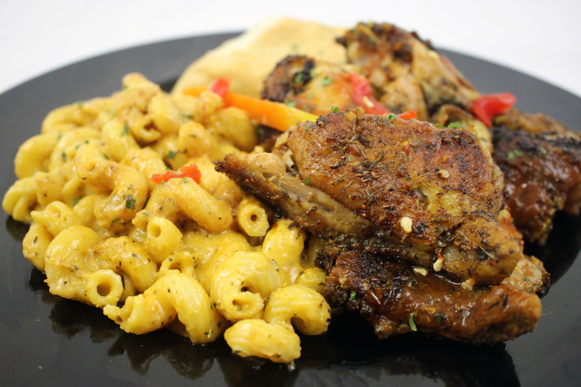 Mac and cheese in a white bowl, garnished with parsley, and next to a spoon.