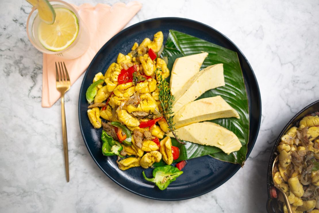 Gnocchi with vegetables and plantain on a blue plate with a drink and fork.