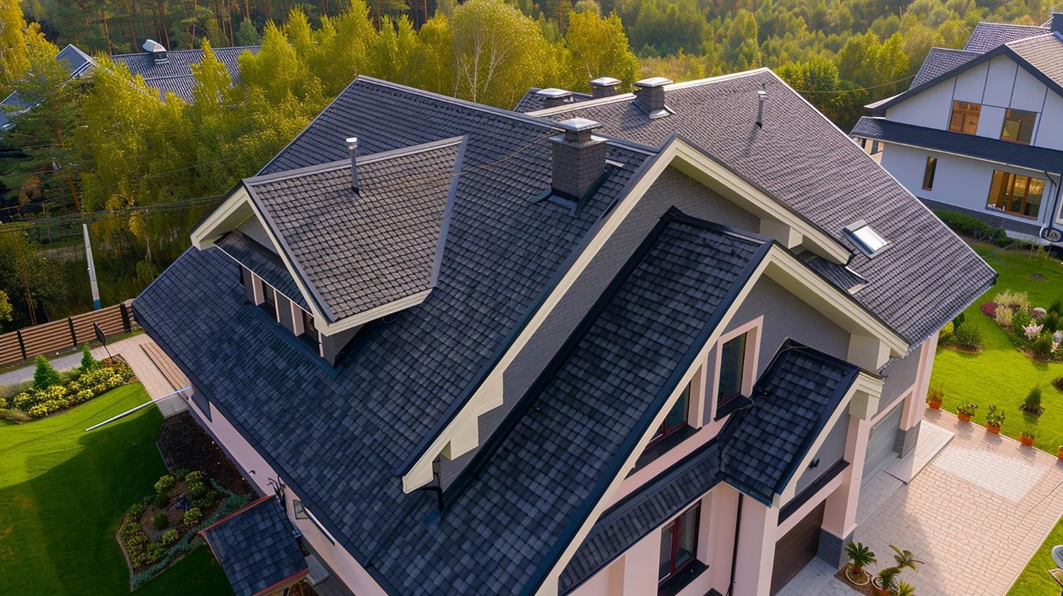 An aerial view of a large house with a blue roof surrounded by trees.